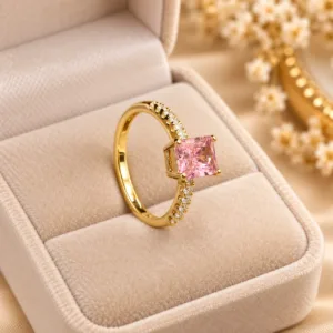 Pink stone gold tone ring with rectangular center stone and sparkling side stones