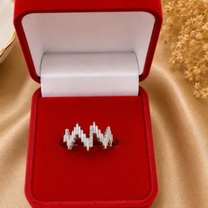 Elegant silver star-shaped ring with sparkling stone detailing, photographed on champagne-beige satin