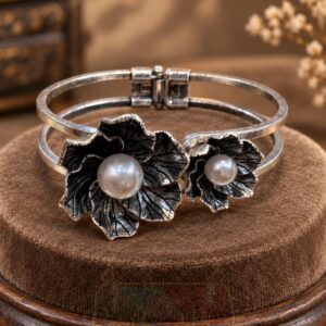 featuring two sculpted flowers, engraved petals, luminous pearl-style centres and a hinged double band.
