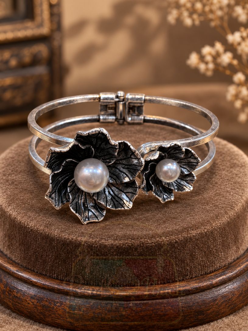 featuring two sculpted flowers, engraved petals, luminous pearl-style centres and a hinged double band. featuring two sculpted flowers, engraved petals, luminous pearl-style centres and a hinged double band.