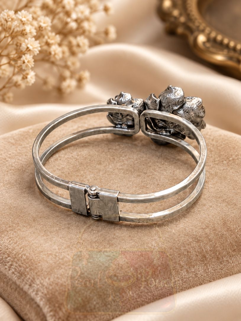 featuring two sculpted flowers, engraved petals, luminous pearl-style centres and a hinged double band. featuring two sculpted flowers, engraved petals, luminous pearl-style centres and a hinged double band.